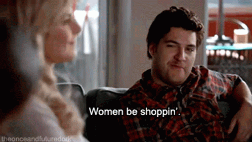 a man and a woman are sitting on a couch and the woman is saying " women be shoppin "